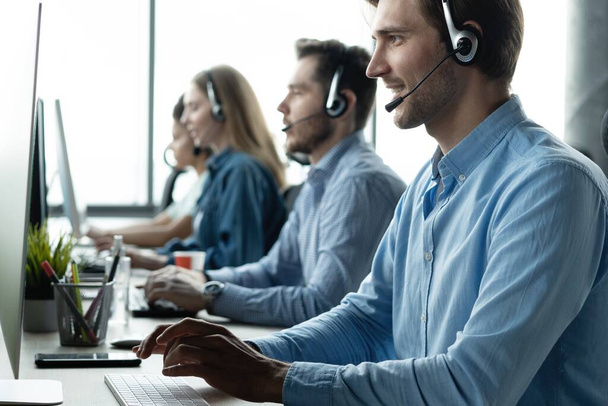 Young handsome male customer support phone operator with headset working in call center - Fotoğraf, Görsel