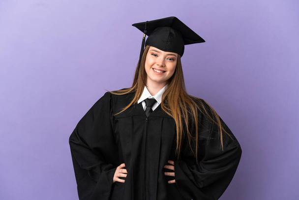 Young university graduate over isolated purple background posing with arms at hip and smiling - Foto, Bild