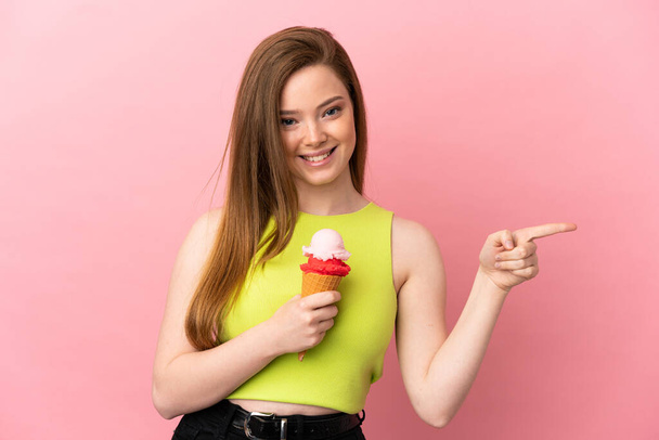 Дівчина-підліток з корнетним морозивом над ізольованим рожевим фоном, спрямованим пальцем в сторону
 - Фото, зображення