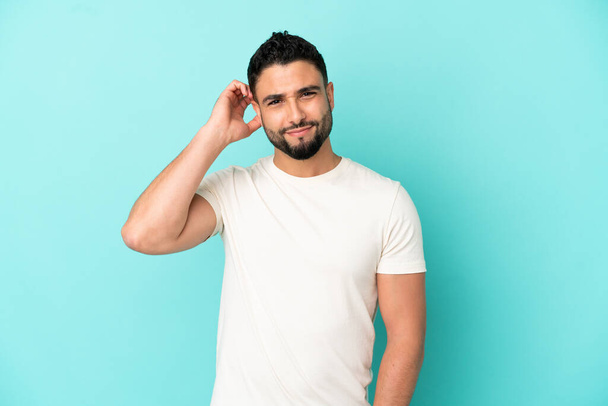 Young arab man isolated on blue background having doubts - Photo, Image
