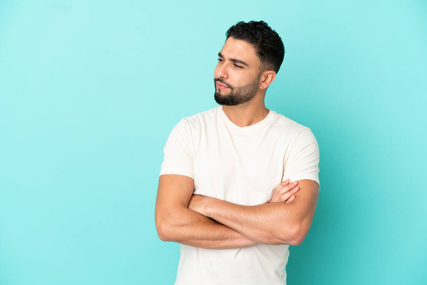 Young arab man isolated on blue background looking to the side - Foto, afbeelding