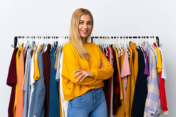 Joven mujer rubia uruguaya en una tienda de ropa con los brazos cruzados y mirando hacia adelante - Foto, Imagen