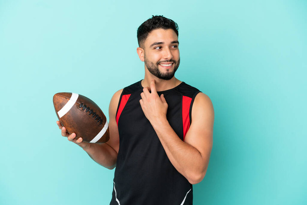 Young arab man playing rugby isolated on blue background looking up while smiling - Photo, image