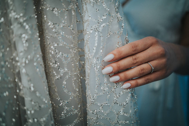 The hand of a bride touching her white bridal dress before wearing it on a wedding day - Valokuva, kuva