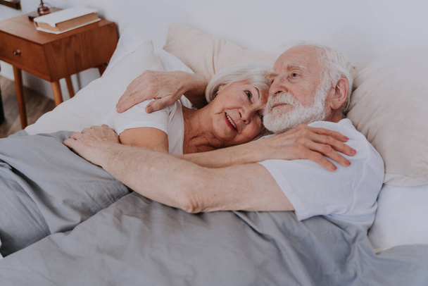 Beautiful senior couple enjoying time together at home - Romantic moments at home, elderly couple in bed at home - Foto, immagini