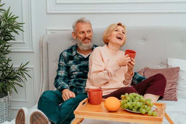 man en vrouw ontbijten op bed met koffie en fruit - Foto, afbeelding