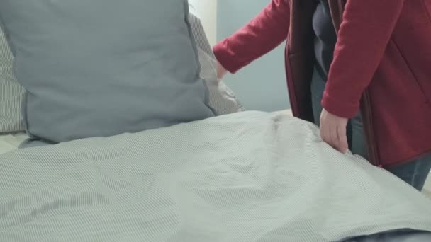 Mulher no hotel endireita roupa de cama no quarto para relaxar após o voo longo - Filmagem, Vídeo