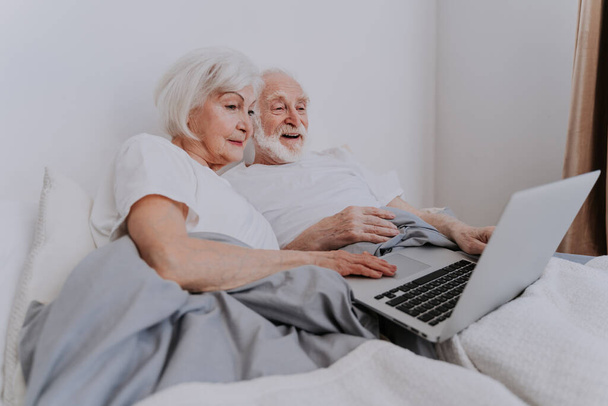 Beautiful senior couple enjoying time together at home - Moder elderly couple surfing the internet on laptop computer - Zdjęcie, obraz