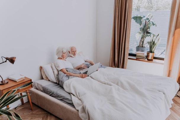 Bella coppia anziana godendo del tempo insieme a casa - Moderna coppia anziana navigare in internet sul computer portatile - Foto, immagini
