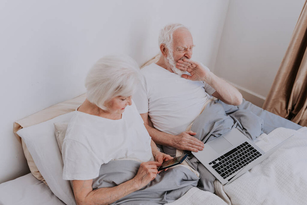 Beautiful senior couple enjoying time together at home - Moder elderly couple surfing the internet on laptop computer - Фото, изображение