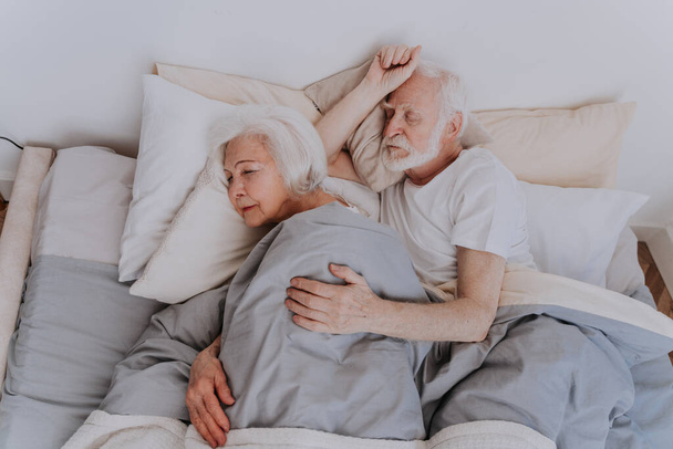 Beautiful senior couple enjoying time together at home - Elderly people sleeping in bed at home - Photo, image