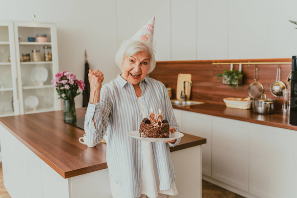 Beautiful senior couple celebrating  anniversary with birthday cake - Elderly couple having birthday party at home - Φωτογραφία, εικόνα