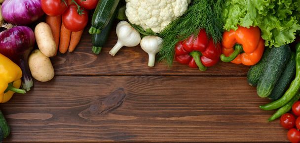 Un ensemble de légumes sur un fond en bois : carottes, pommes de terre, courgettes, paprika, concombre, ail, tomates, laitue. Vue du dessus. Espace de copie - Photo, image