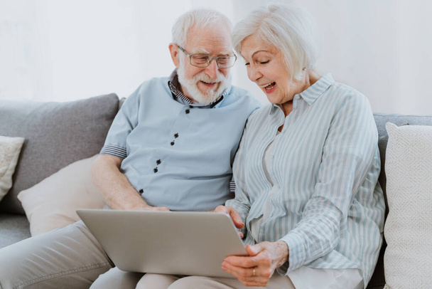 Elderly couple shopping online on internet with computer laptop at home - Beautiful happy senior people using pc and social network apps - Foto, Imagem