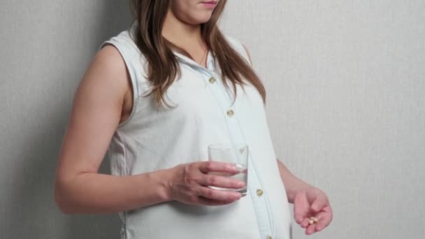 Nuori raskaana oleva nainen juo lääkettä veden kanssa - Materiaali, video