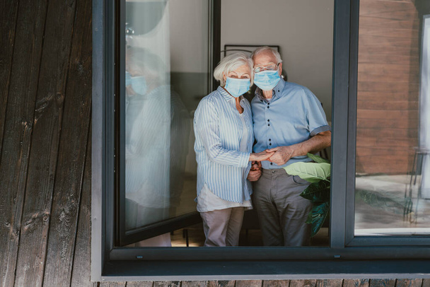 Elderly couple with protective face masks at home during covid-19 pandemic quarantine - Old people in quarantine respection social distance and isolation on coronavirus virus spread - Fotografie, Obrázek