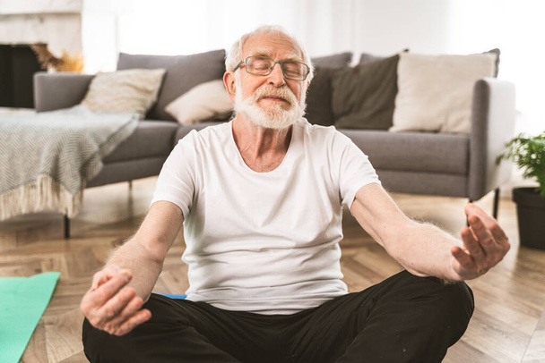Sportive senior man doing fitness and relaxation exercises at home - Elderly people training to stay healthy and fit - Foto, imagen