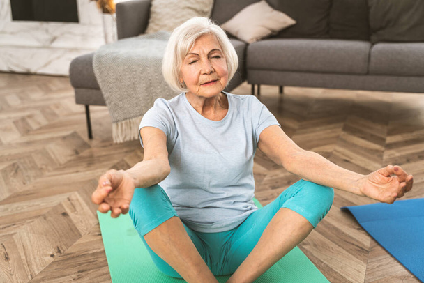 Sportive senior woman doing fitness and relaxation exercises at home - Elderly people training to stay healthy and fit - Foto, Bild