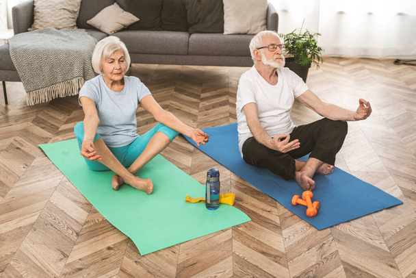 Sportive senior couple doing fitness and relaxation exercises at home - Elderly people training to stay healthy and fit - Fotoğraf, Görsel