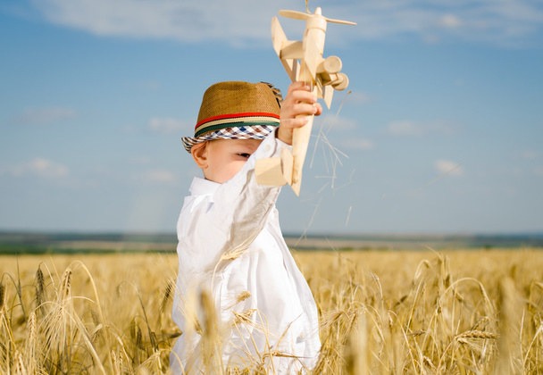 少年が麦畑でおもちゃの飛行機を飛んでいます。 - 写真・画像