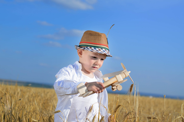 Kleiner Junge fliegt ein Spielzeugflugzeug in einem Weizenfeld - Foto, Bild