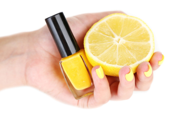 Female hand with stylish colorful nails holding fresh lemon and bottle with nail polish - Φωτογραφία, εικόνα