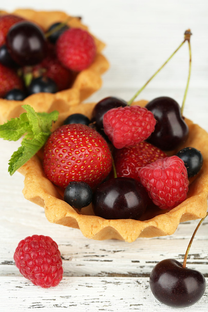 Tasty tartlets with berries on wooden table - 写真・画像