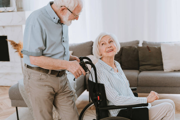 Инвалидная пожилая женщина на инвалидной коляске - пожилая пара дома, партнер, возвращающийся из больницы в состоянии выздоровления - Фото, изображение