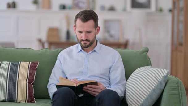 Giovane uomo lettura libro a casa - Foto, immagini
