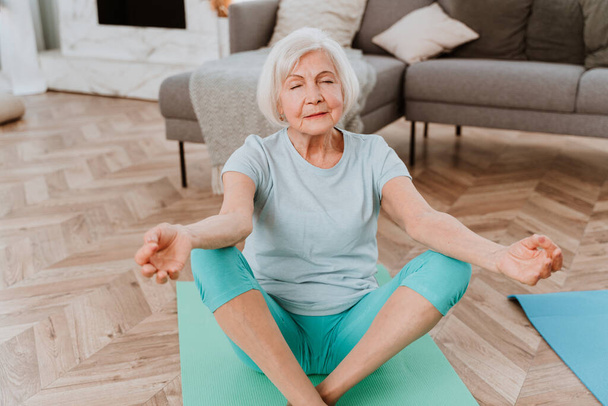 Sportive senior woman doing fitness and relaxation exercises at home - Elderly people training to stay healthy and fit - Fotografie, Obrázek