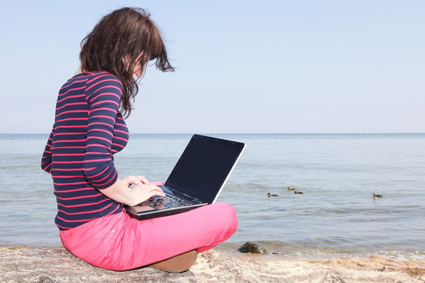 genç kadın bir dizüstü bilgisayar ile sahilde - Fotoğraf, Görsel
