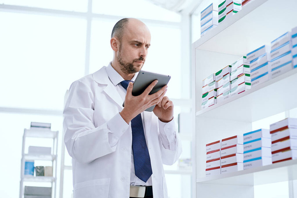 pharmacist using a digital tablet to complete an online order. - Foto, Bild
