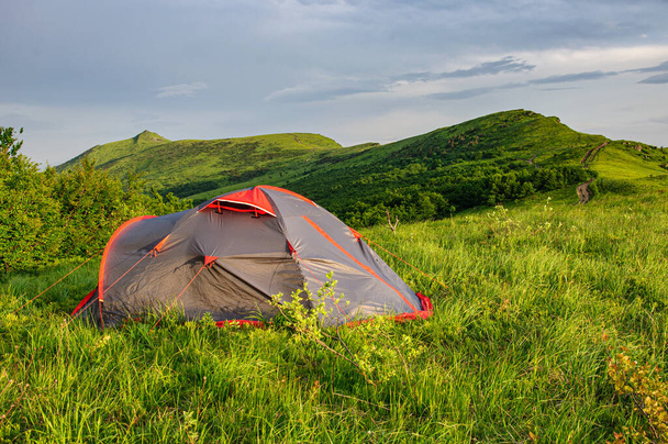 Suuri harmaa teltta seisoo vihreällä rinteellä Karpaattien vuorten juurella. Ukraina - Valokuva, kuva