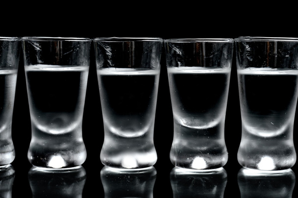 Many glasses of vodka isolated on black background - Foto, afbeelding