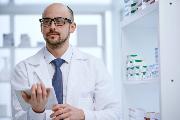 pharmacist with a digital tablet standing in his pharmacy. - 写真・画像