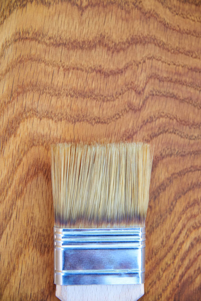 Peindre une surface en bois avec du vernis, un pinceau sur une planche de chêne, vue de dessus, espace de copie. - Photo, image