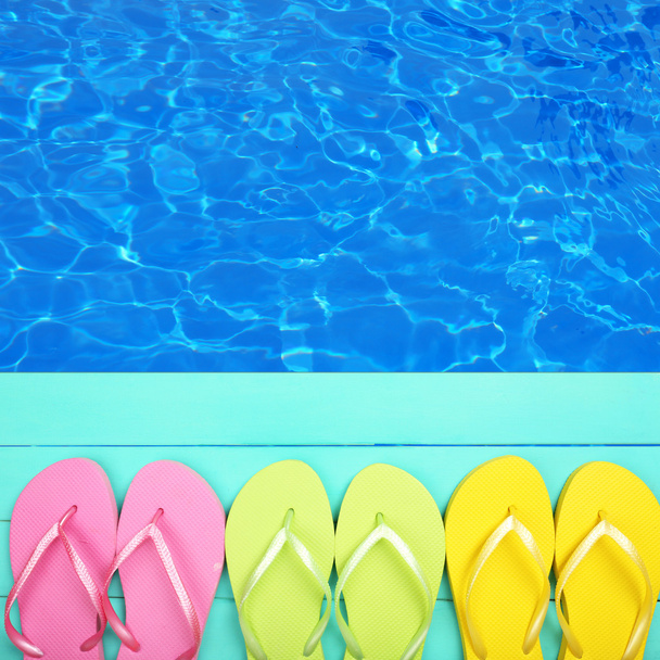Colored flip flops on wooden platform beside sea - Φωτογραφία, εικόνα
