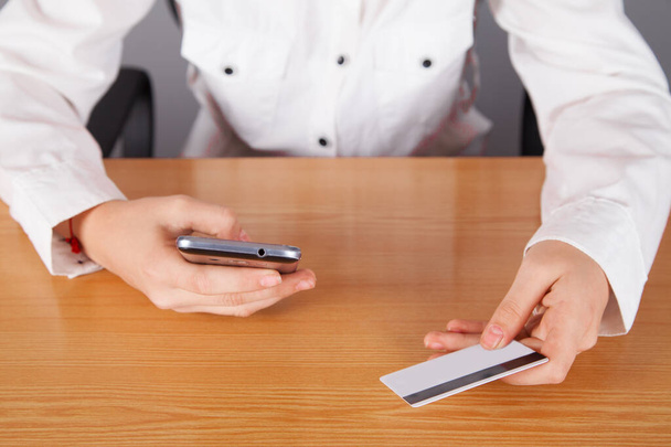Бизнес-леди, держащая смартфон с кредитной картой, для оплаты интернет-покупок. - Фото, изображение