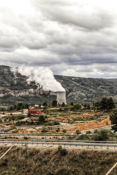 Chimeneas humeantes en la central nuclear de Cofrentes entre montañas en Valencia, España - Foto, imagen