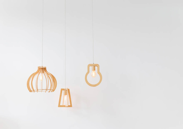 Suspended wooden lamp hanging near white wall in light modern interior - Zdjęcie, obraz