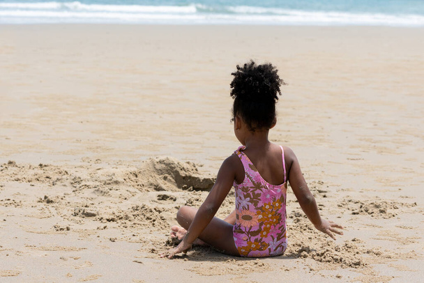 Iloinen afroamerikkalainen poika leikkii hiekalla trooppisella rannalla kesäviikonloppuna. Leikkisä lapsi nauttii meren rannalla kesälomilla. Käsitteet yhdessäolo. - Valokuva, kuva