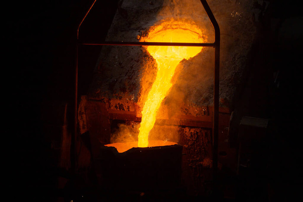 процесс наполнения ковша расплавленной горячей сталью из печи дымом - крупным планом с избирательным фокусом - Фото, изображение