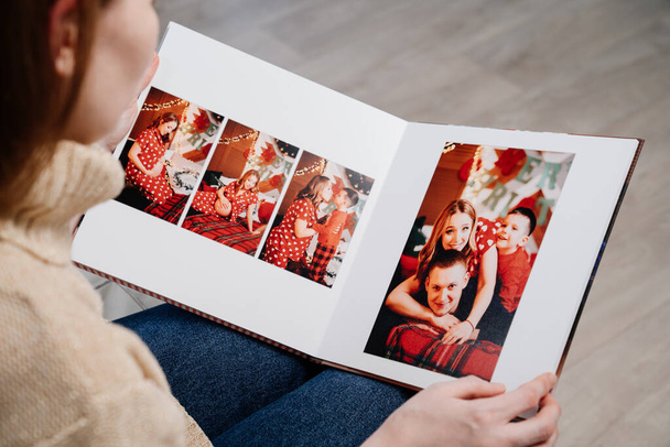 woman flips through the pages of photobook from a new years family photo shoot - Фото, изображение