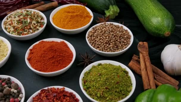 Kleurrijke kruiden en specerijen om te koken. Indiase kruiden. Op een zwarte achtergrond. Bovenaanzicht - Video