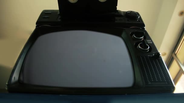 Männliche Hand beim Einfügen einer VHS in einen Videorekorder und einen alten Fernseher mit Green Screen. Sie können den grünen Bildschirm durch das gewünschte Filmmaterial oder Bild ersetzen. Sie können dies mit dem Keying-Effekt in After Effects oder jeder anderen Videobearbeitungssoftware tun (siehe Tutorials).).  - Filmmaterial, Video
