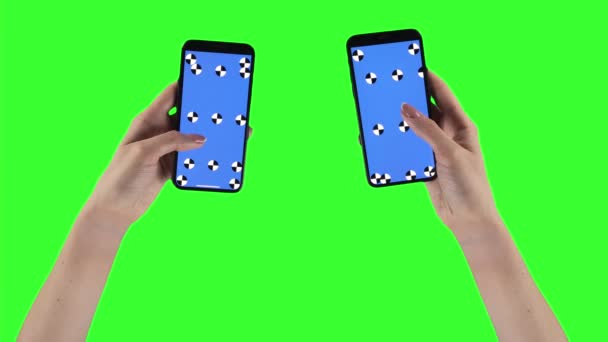 Woman holds two smartphones on green screen background with alpha compositing on displays - Video