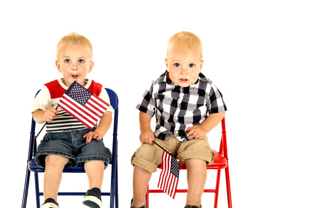 two cute blond boys holding American flags sitting - Foto, Imagem