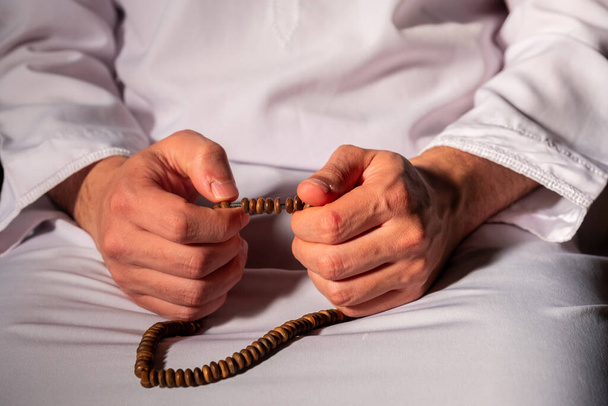 Muslim man holding rosary after pray  wearing dishdash - 写真・画像