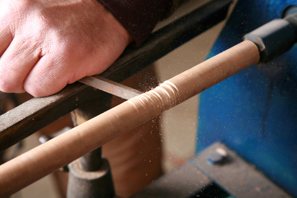 木材加工。ラテだ。木の労働者が彼の旋盤でプロジェクトに取り組んでいます。旋盤は、世界中のあらゆる種類のプロジェクトの木材労働者や金属労働者によって使用されています。木材加工はビジネスと趣味です。熟練した木工職人が旋盤で木を回転させます。木 - 写真・画像