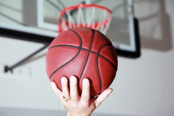 Μπάλα μπάσκετ. Μια μπάλα μπάσκετ στο καλάθι. Σκοράροντας γκολ στο καλοκαιρινό γήπεδο κατά τη διάρκεια ενός αγώνα μπάσκετ. Μπάσκετ μέσα από το καλάθι κατά τη διάρκεια του αγώνα.  - Φωτογραφία, εικόνα
